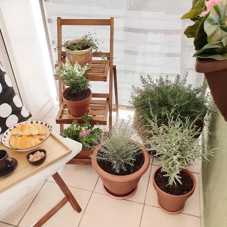 Small balcony setup with ceramic potted plants and a wooden plant stand.