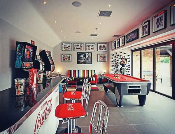Modern game room with a Coca-Cola themed bar, pool table, arcade games, and wall art