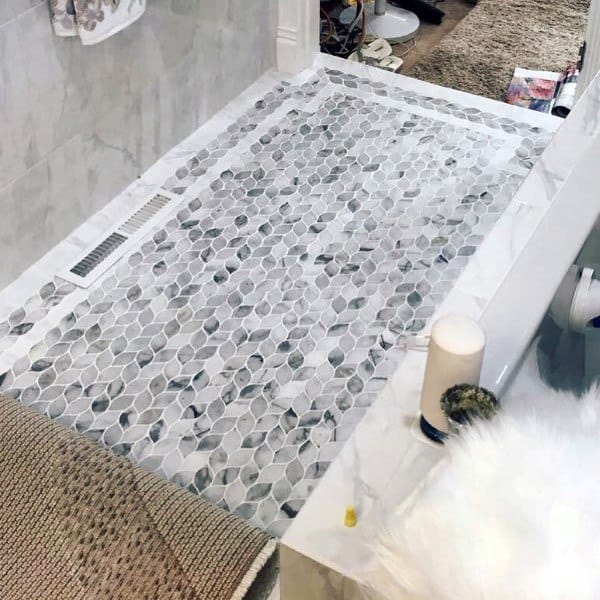 Bathroom with intricate gray and white mosaic floor tiles and marble accents.
