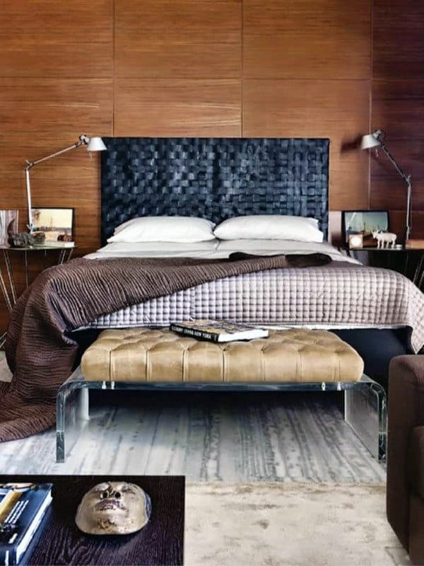 Modern bedroom with a brown headboard, twin lamps, and a bench at the foot of the bed