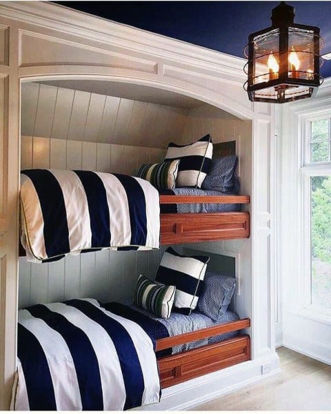 Bunk beds with navy-striped bedding, small wooden drawers, and a lantern light fixture