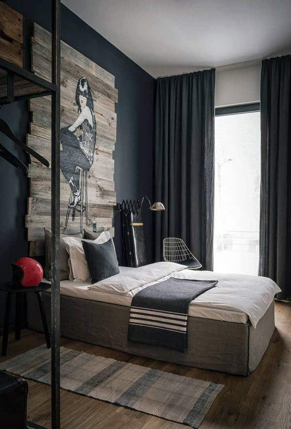 Modern bedroom with dark walls, bed, industrial decor, and wall art of a woman