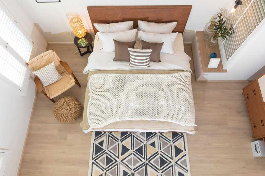 Cozy small bedroom with layered bedding, knit blanket, and geometric patterned rug.