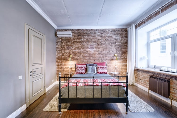 Small bedroom featuring exposed brick walls and an unfinished ceiling, with simple yet cozy furniture and a comfortable atmosphere