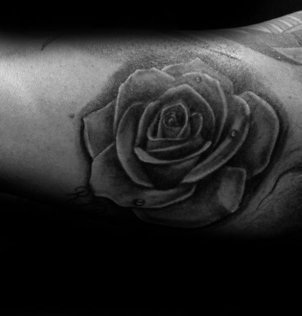 Black and gray tattoo of a detailed rose with water droplets