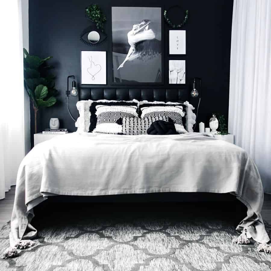 Modern bedroom with black accent wall, monochrome bedding, gallery art, and soft lighting.