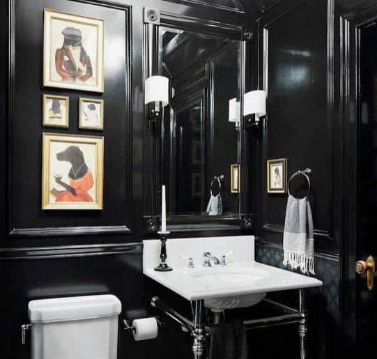 Glossy black bathroom with white sink, framed artwork, and elegant wall sconces.