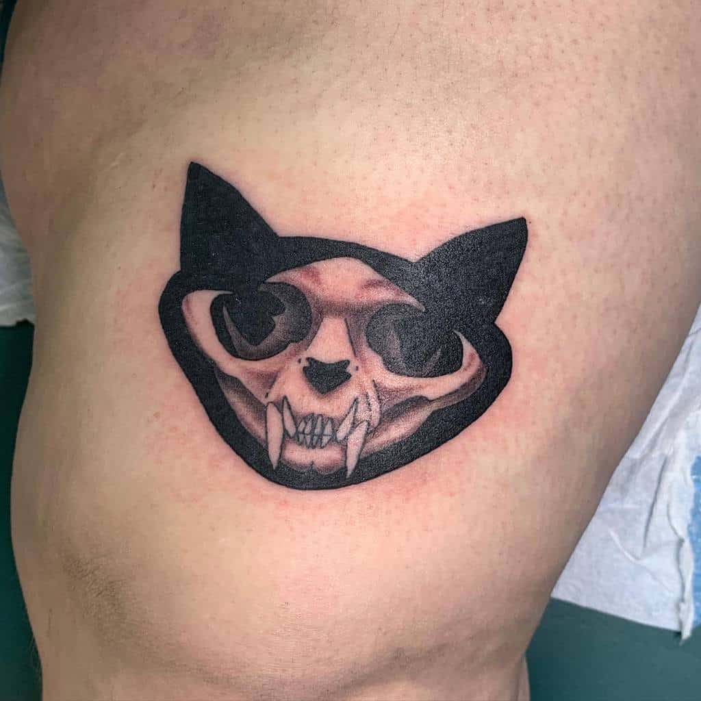 Tattoo of a detailed cat skull with large fangs inside an outlined cat silhouette