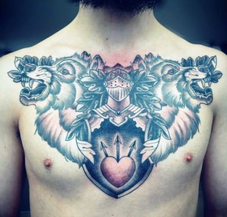 Chest tattoo of two wolves and a knight's helmet on a shield with heart and arrows