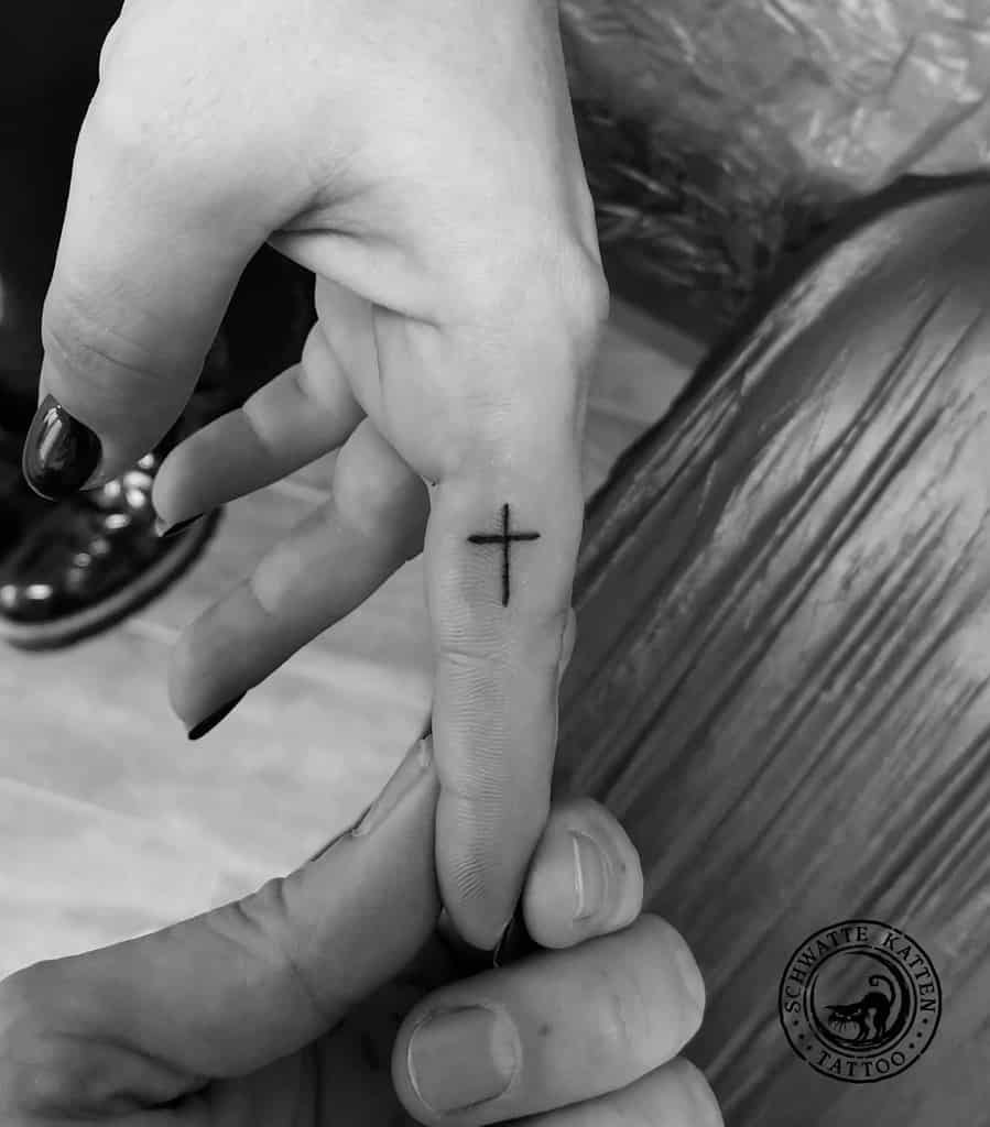 Small cross tattoo etched elegantly on a finger