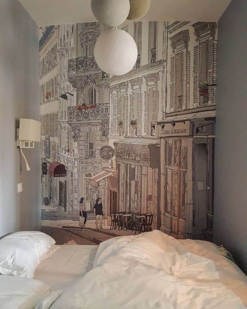 Cozy bedroom with a large mural of a Paris street scene on the wall, featuring buildings and a small café