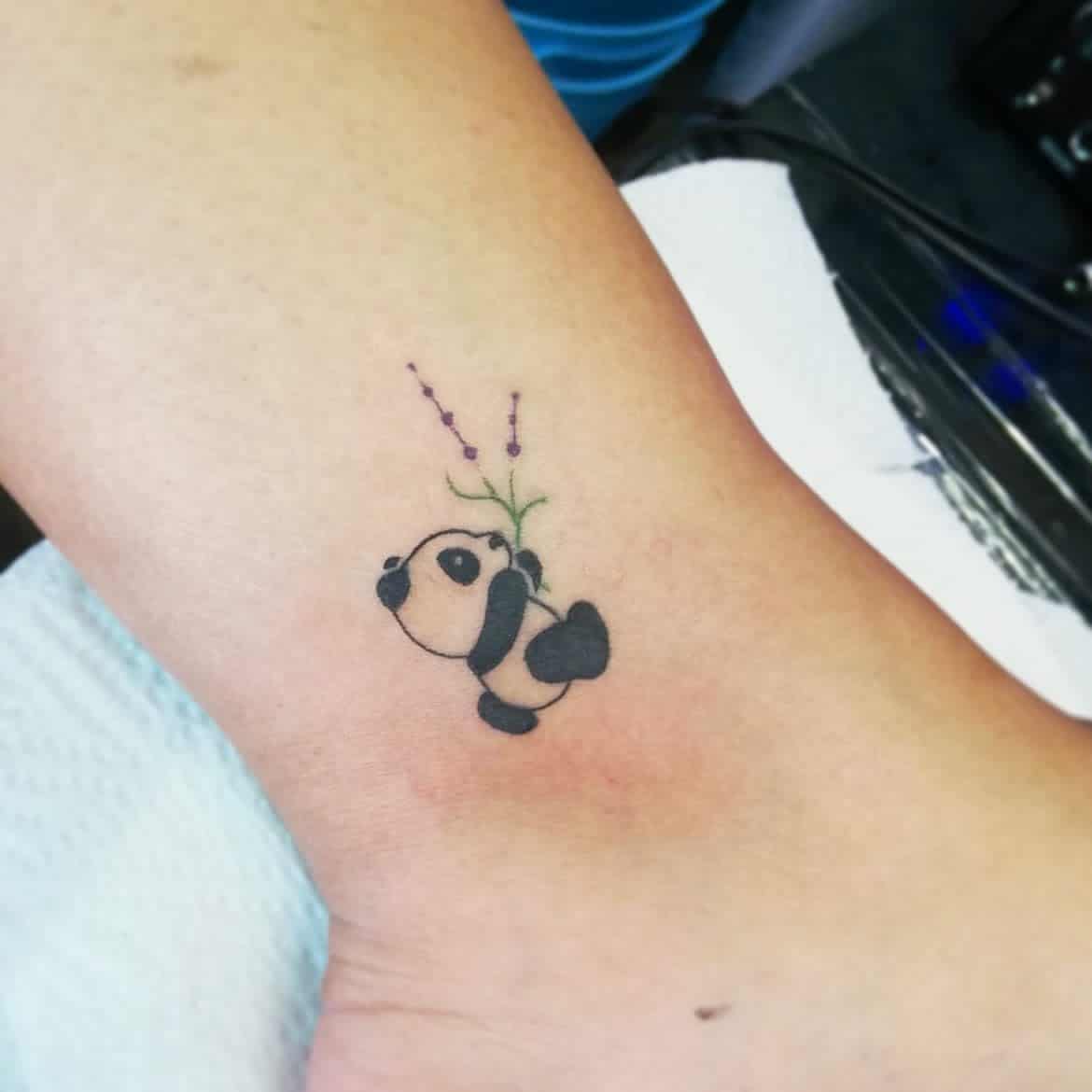 Adorable tiny panda tattoo holding some lavender flower