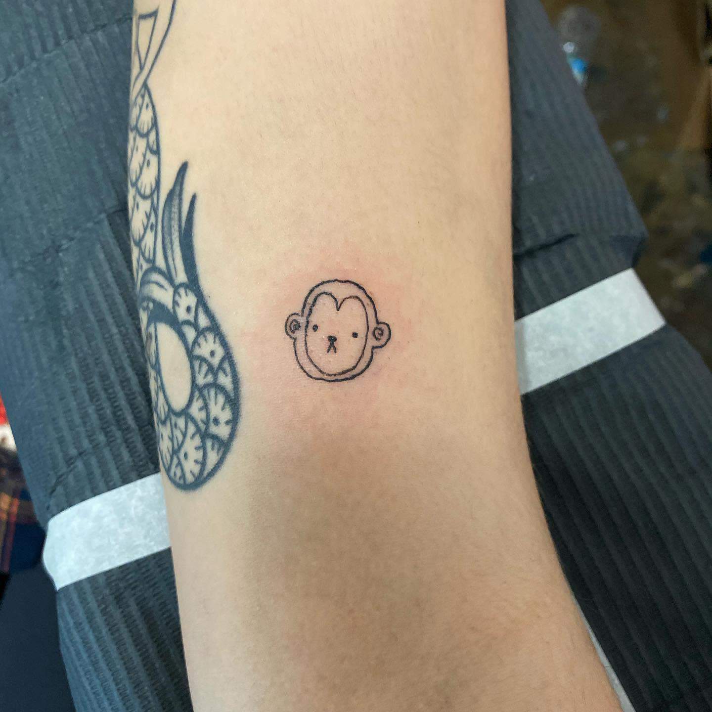 Minimalist monkey face tattoo with simple black outlines