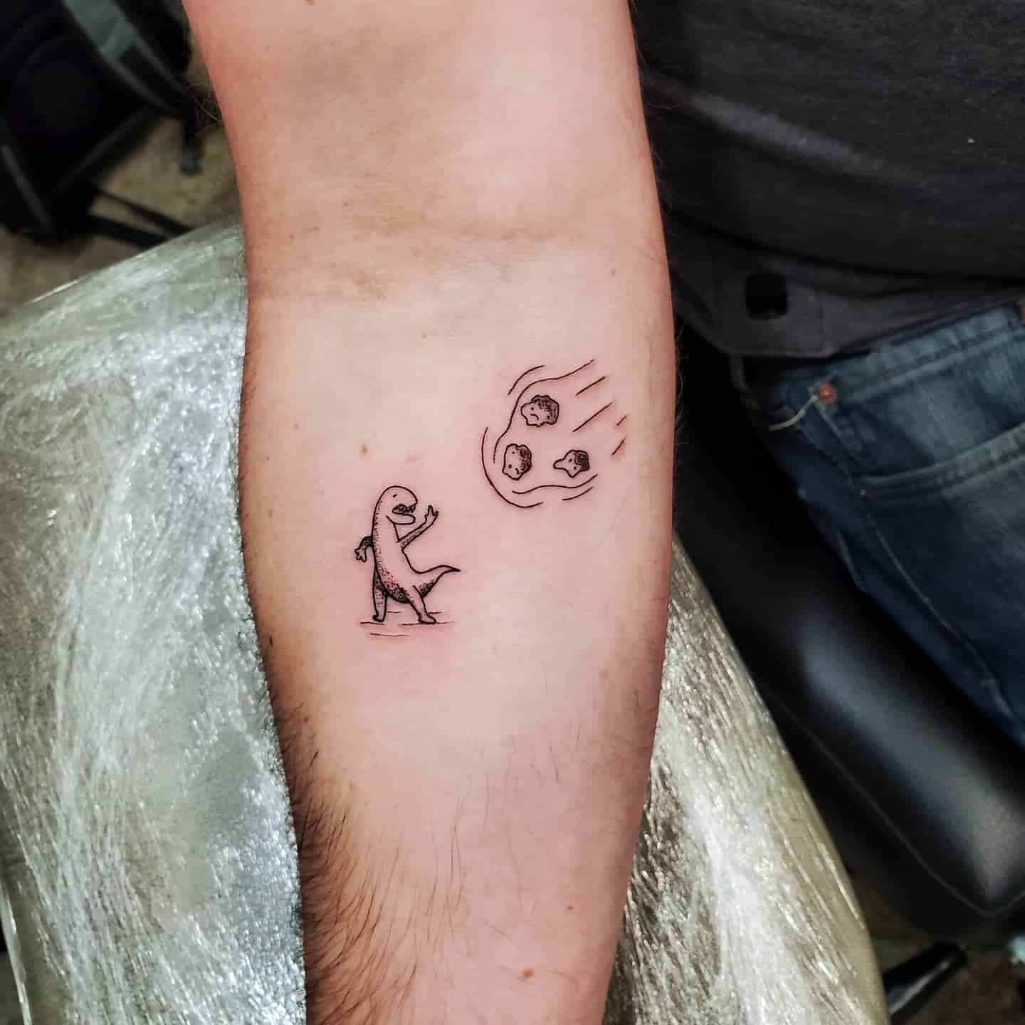 Funny minimalist dinosaur tattoo waving at an incoming meteor