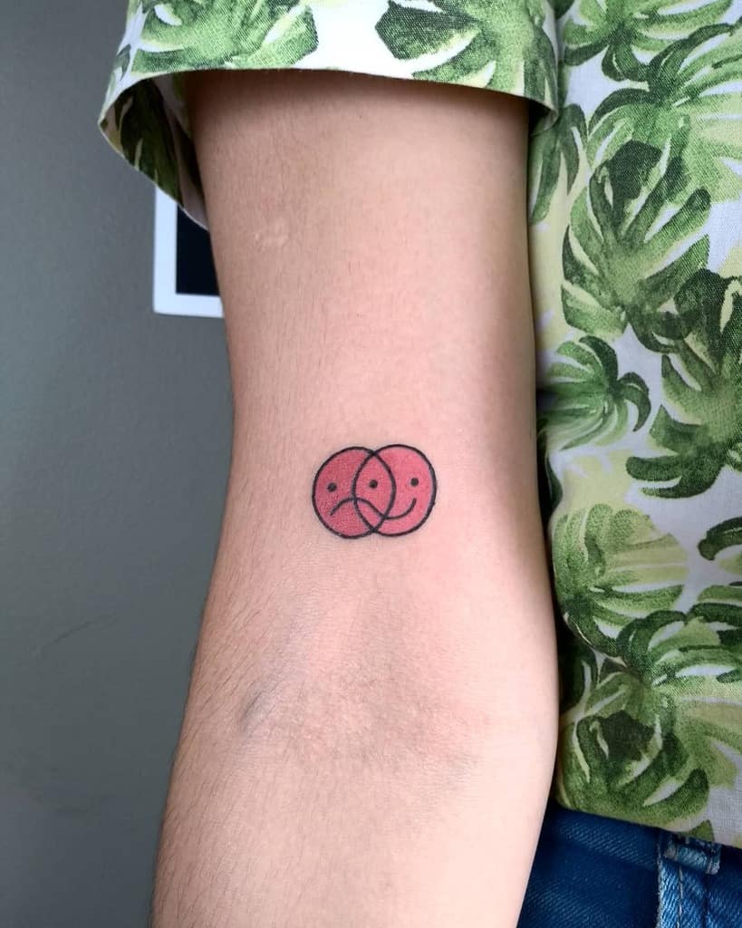 Minimalist red overlapping smiley and sad face tattoo