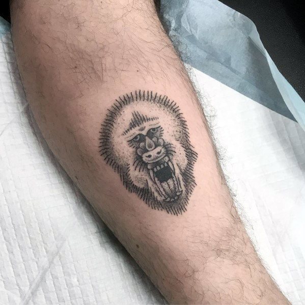 Small blackwork baboon tattoo with bold line shading and a fierce open-mouthed expression, creating a striking yet minimalist leg design.