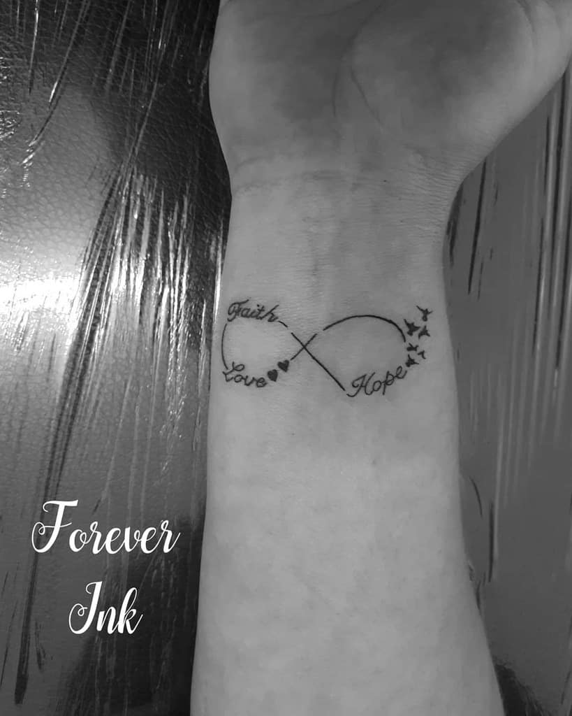 Wrist tattoo with "Faith," "Hope," "Love" in an infinity symbol with hearts and stars