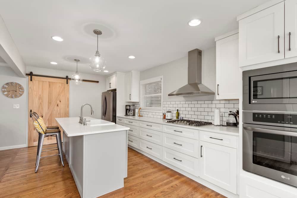 large white kitchen white tile splashback island sliding barn door 