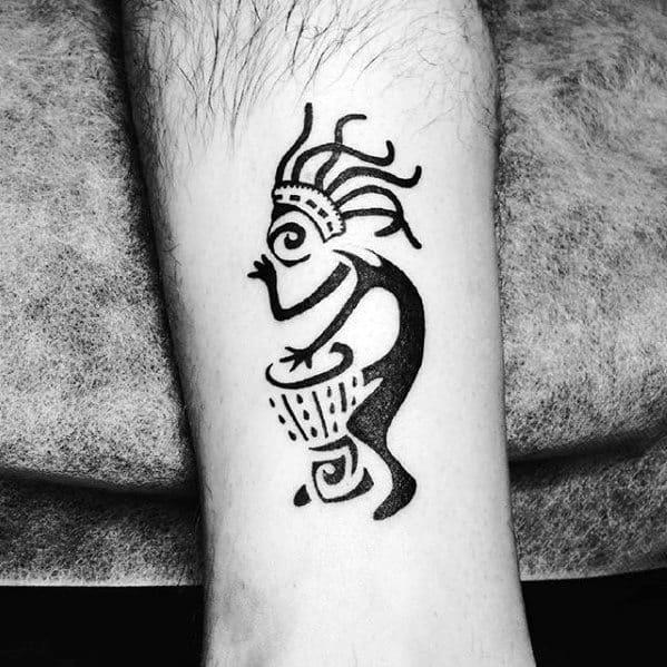 Bold black Kokopelli tattoo with spiral and geometric patterns, showing the figure drumming with expressive hair and motion lines.