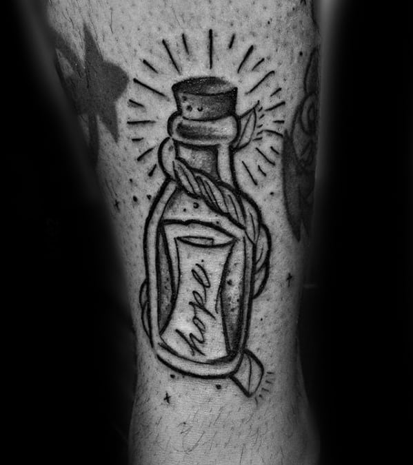Tattoo of a message in a bottle with "hope," wrapped in rope, emitting rays of light