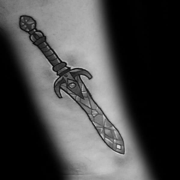 Skyrim-themed black and white tattoo of a detailed sword on skin