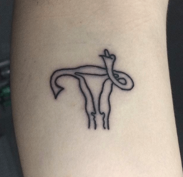 A simple black ink tattoo of a uterus with fallopian tubes resembling hands and a snake intertwined, blending anatomy with symbolism.