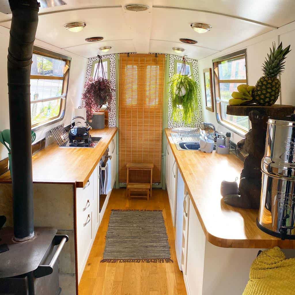 small galley kitchen white cabinets wood countertop hanging plants pineapple