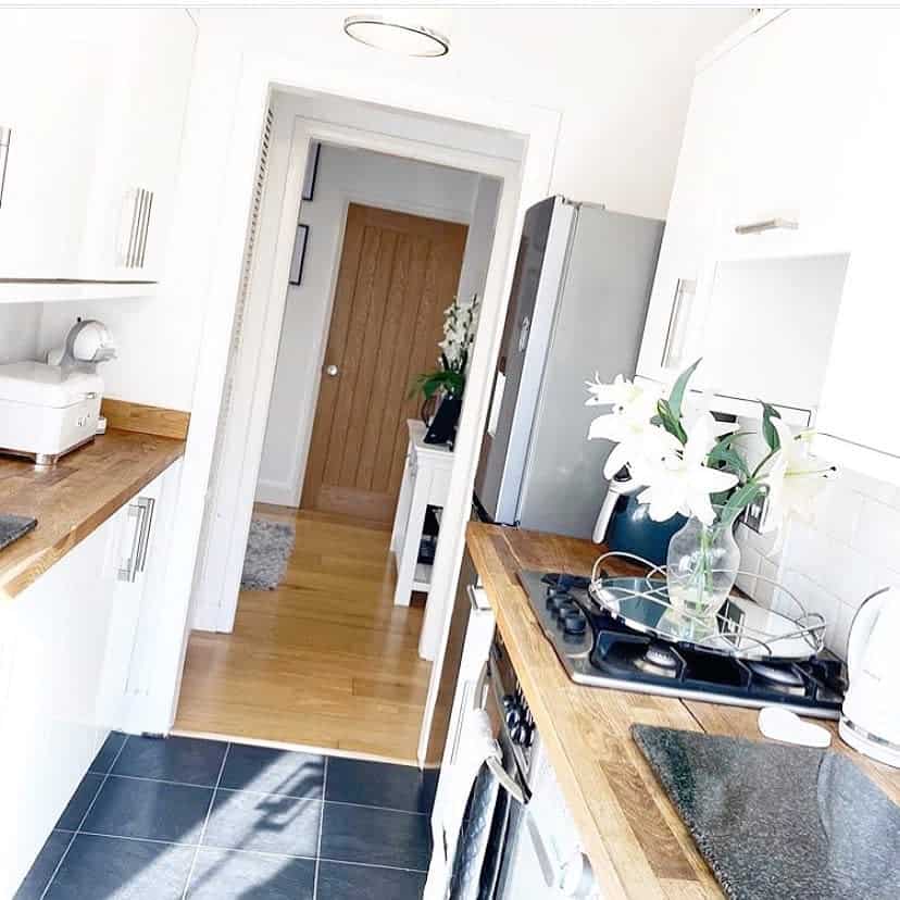 small country style galley kitchen white cabinets wood bench tops