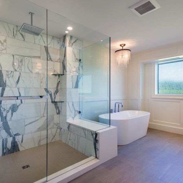 Modern bathroom with marble shower, freestanding tub, chandelier, and large floor-to-ceiling window