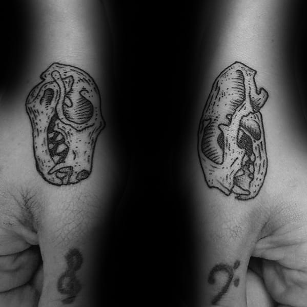 Two forearm tattoos depicting detailed, small animal skulls