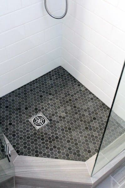 Shower with dark hexagon floor tiles, white subway wall tiles, and glass enclosure.