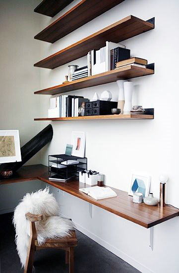 Minimalist home office with wooden shelves, a desk, black and white decor, and a chair with a fur seat cover