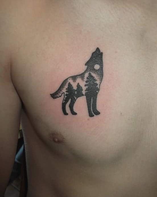 Silhouette tattoo of a howling wolf with pine trees on a man's upper chest