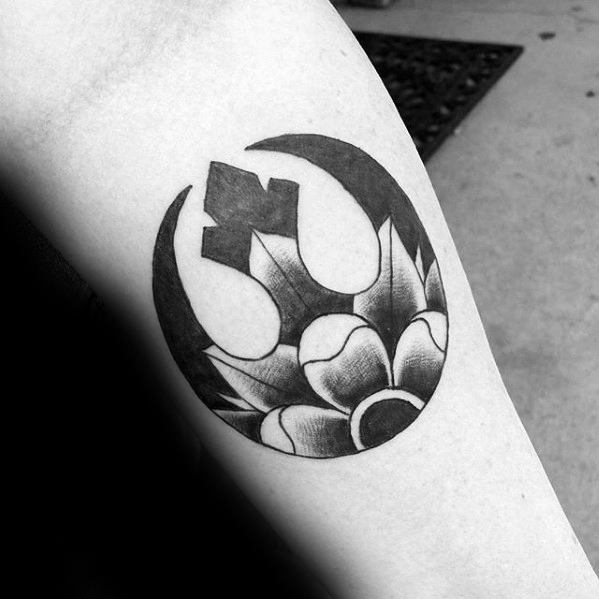 Black and gray Rebel Alliance tattoo on the forearm, featuring a bold flower design at the base