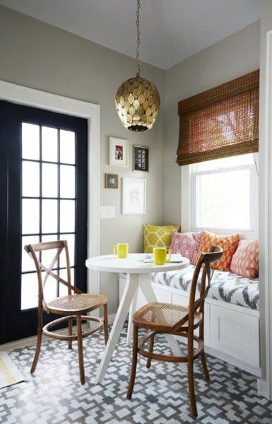Cozy nook with a round table, two chairs, colorful cushions, patterned floor, and a gold pendant light
