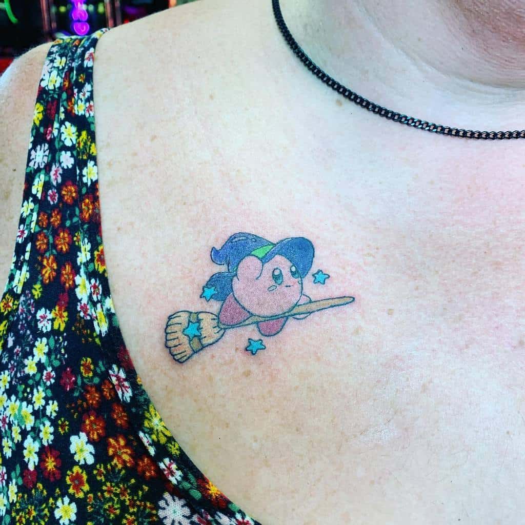 Kirby tattoo dressed as a witch, flying on a broomstick with a starry trail