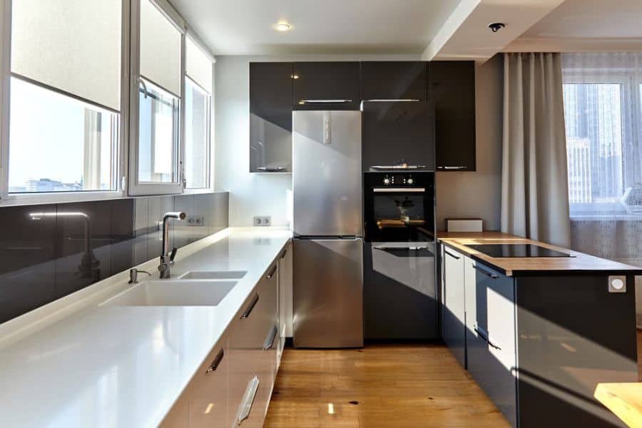 Modern kitchen with black cabinets, white countertops, and built-in stainless steel appliances.