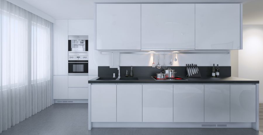 Sleek white kitchen with black countertops, built-in oven, and minimalist design.