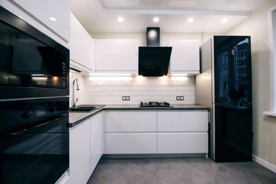 Modern kitchen with black appliances, white cabinets, and a sleek black range hood.