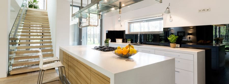 Spacious kitchen with white island, wooden drawers, and modern glass staircase.