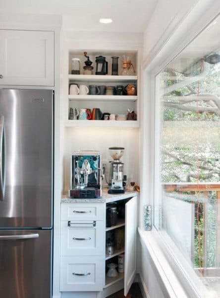Built-in white coffee bar with espresso machine, grinder, open shelves, and natural light.