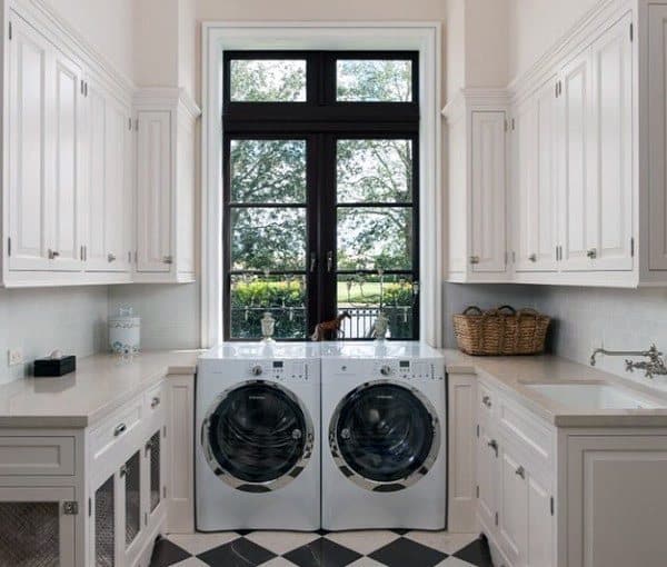 Bright laundry room with white cabinetry, checkered flooring, and a large window for natural light.