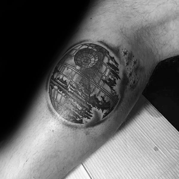 Death Star tattoo with grayscale trees and stars silhouette on an arm