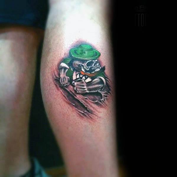 Tattoo of a skeleton leprechaun in a green hat bursting through the skin, with clenched fists and a fierce, animated expression.