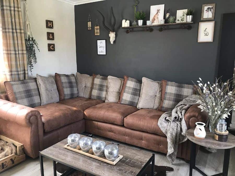 Cozy living room with brown sectional sofa, decorative pillows, wall art, and a rustic coffee table