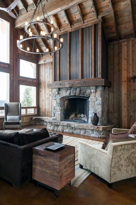 Rustic log cabin living room with stone fireplace, vaulted ceiling, and elegant chandelier.