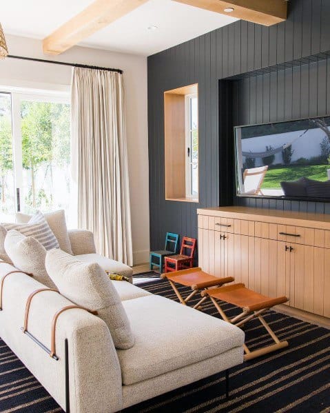 Cozy lounge with white sofa, striped rug, wall-mounted TV, and wooden accents.