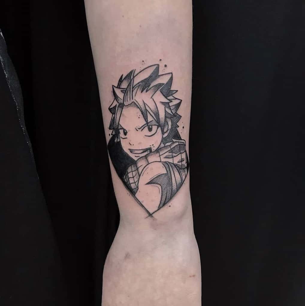 Black and grey tattoo of Natsu Dragneel from Fairy Tail on the forearm, featuring bold shading and a confident expression within a geometric shape.