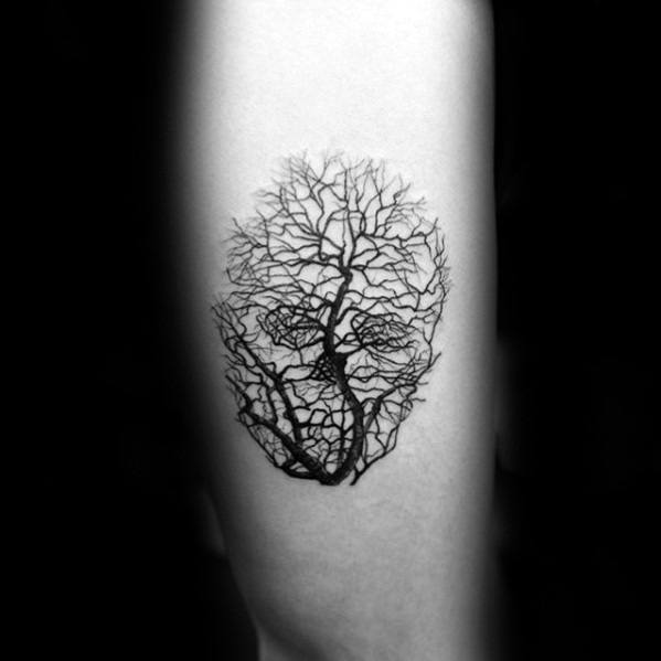 Minimalist tree tattoo with bare branches forming the shape of a skull, blending natural design with subtle dark symbolism.