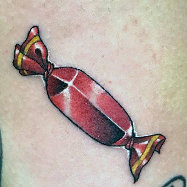 Realistic wrapped candy tattoo with detailed shading and highlights, creating a glossy, three-dimensional effect on the skin.